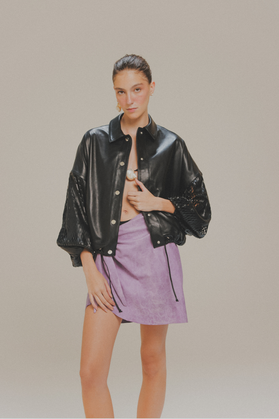 Chamarra bomber de piel de cordero negra con mangas laser cut de Amkie Gamus, vista en modelo.