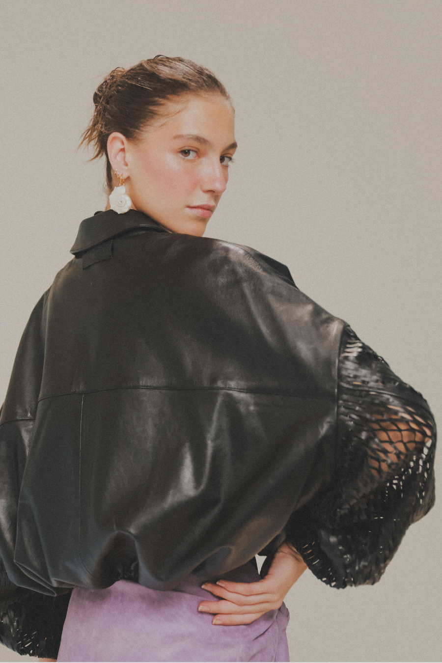 Chamarra bomber de piel de cordero negra con mangas laser cut de Amkie Gamus, vista detalle.