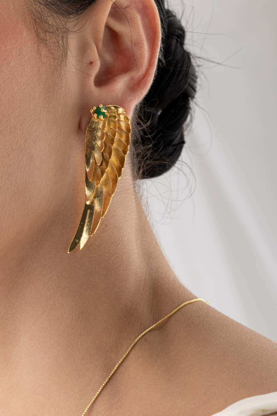 Aretes de oro 24K con esmeralda y diseño de alas de ángel.