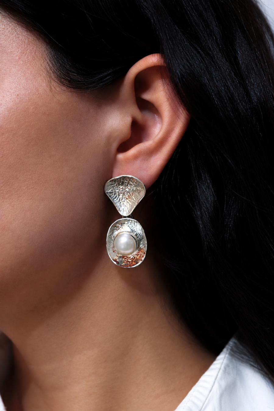 Aretes Centro de KARIZIA en plata .925 con cuerpos articulados, textura irregular y perla central vista en modelo.