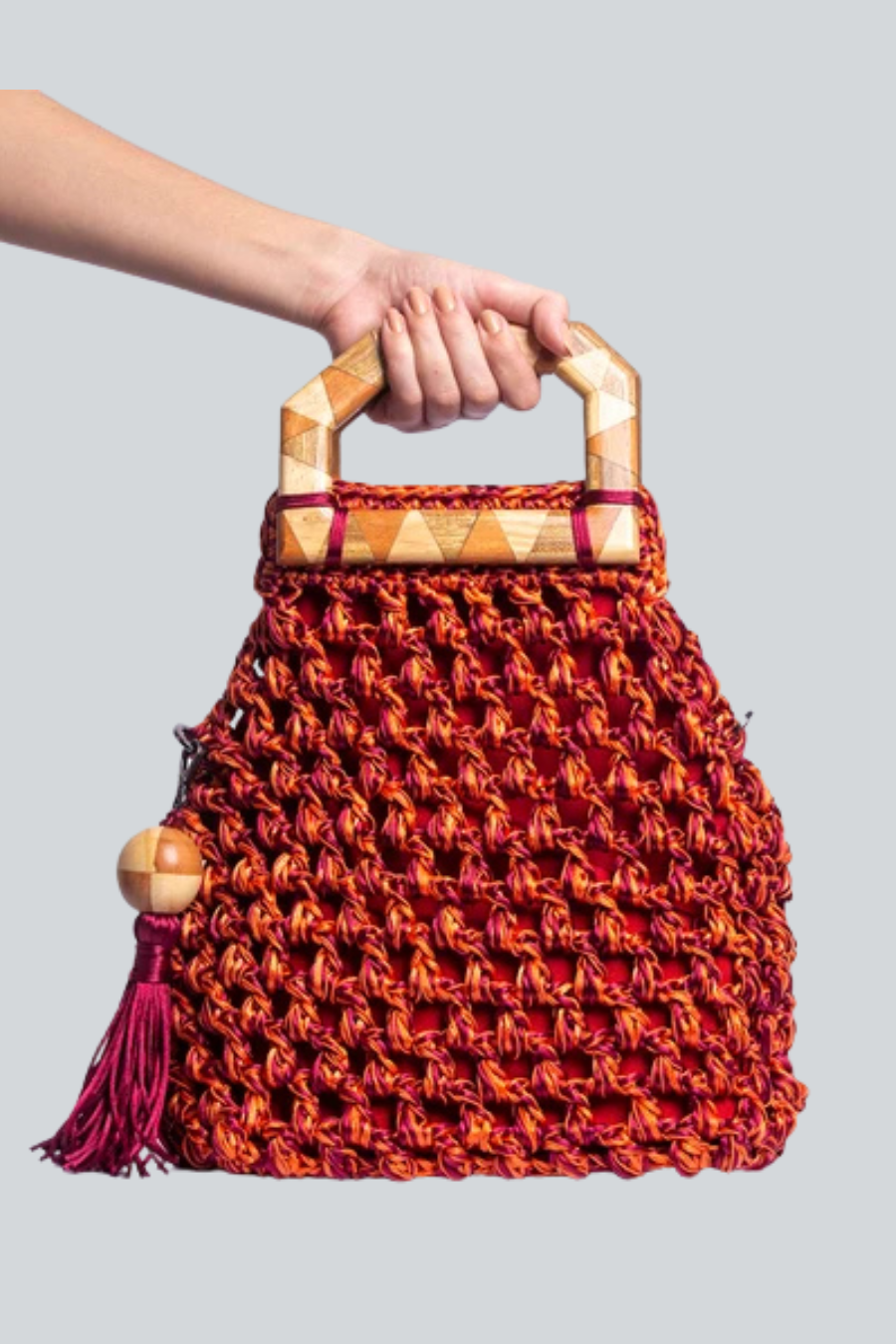 Bolsa Cabana tejida de Catarina Mina con asa de madera color naranja.