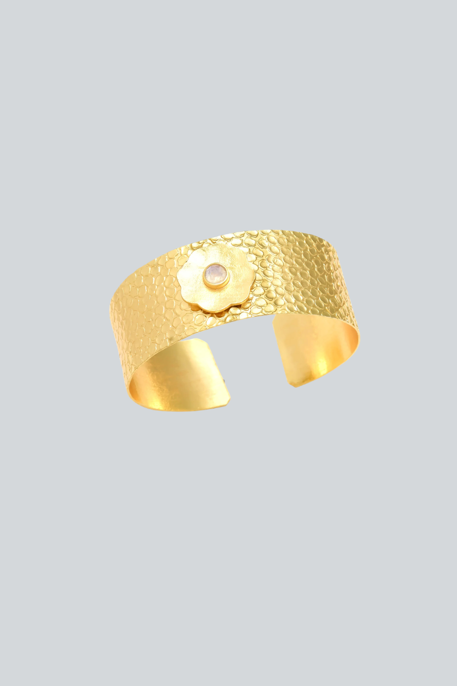 Brazalete martillado de Mestiza Joyas con flor dorada y piedra natural circular, diseño flexible y ajustable.